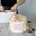 Kage med glat creme, macarons og blomster