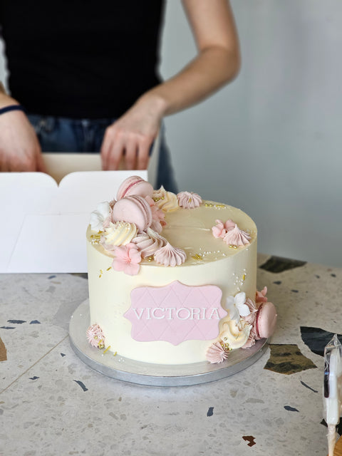 Kage med glat creme, macarons og blomster