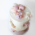 Kage med glat creme, macarons og blomster